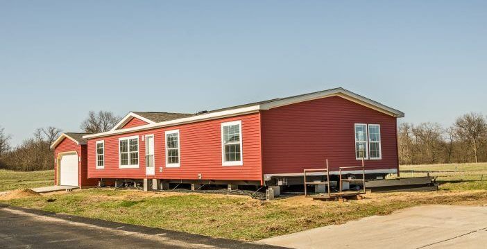 New manufactured home with red vinyl siding and windows with white lineals