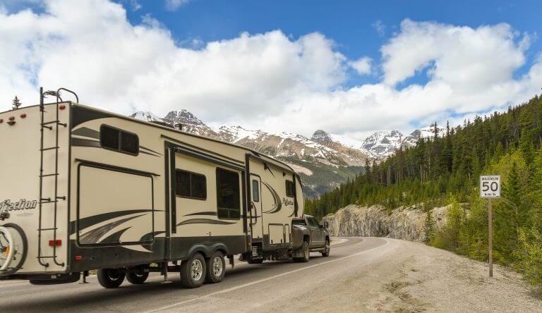 Columbia Icefield, Alberta, Canada - June 2018: Pickup truck towing a big camping trailer on a road through the Columbia Icefield area in Alberta, Canada.