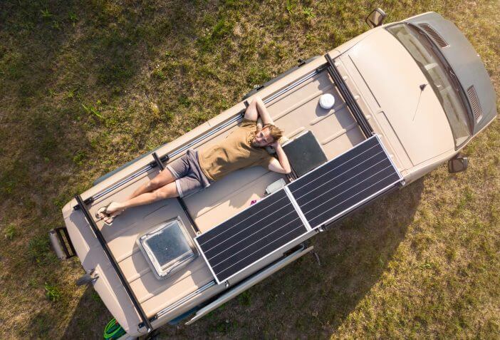 Top down view of a man relaxing on top of a DIY build camper van.