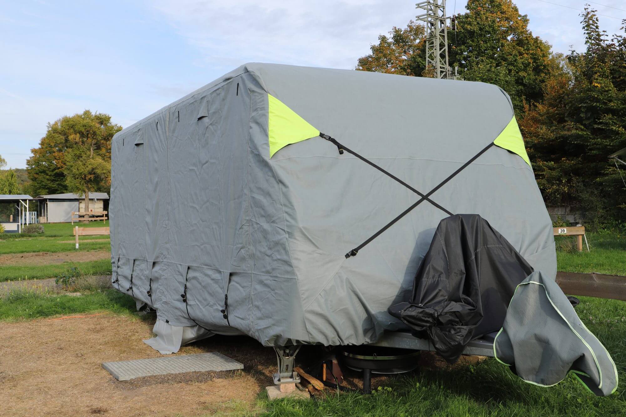 A caravan is winterized with a gray weatherproof tarpaulin