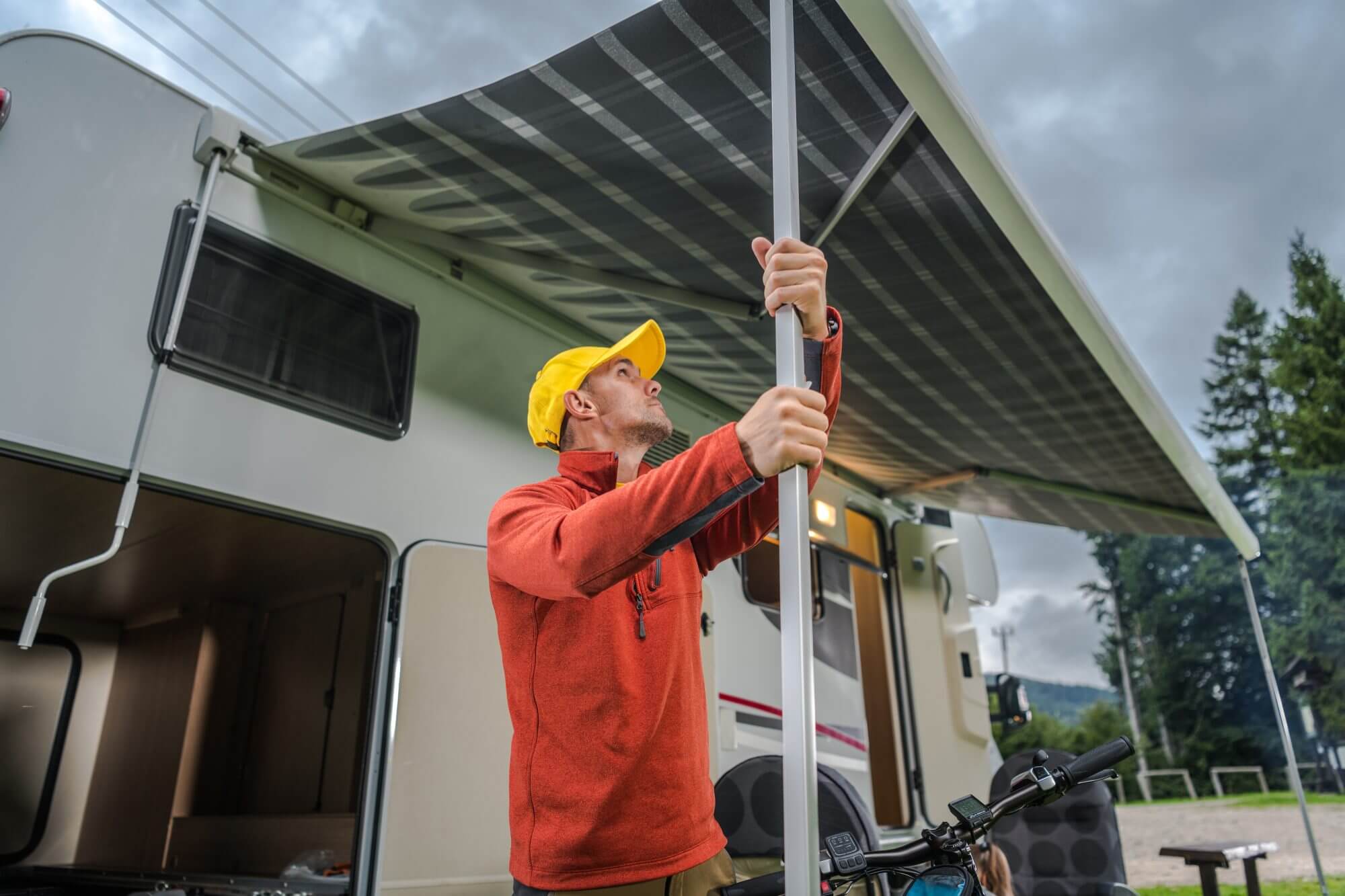 RV Motorhome Awning Extending by Caucasian Camper in His 30s. Travel Industry.