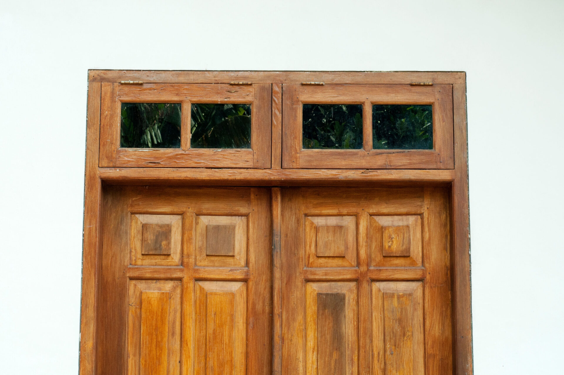 A white wall with old wooden doors and small windows.